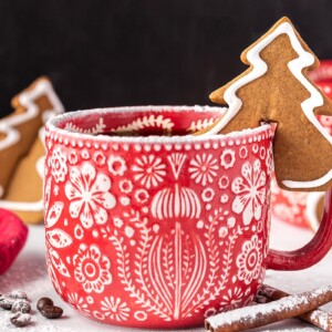 Tree-shaped Gingerbread Cookie Mug Topper on the rim of a red and white mug