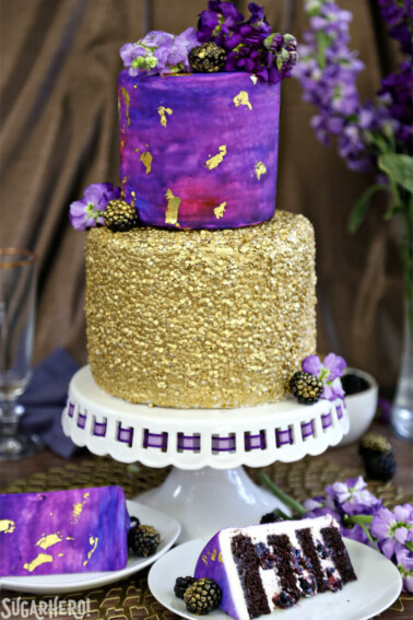 Close up of a Gold Sequin Watercolor Cake wit 2 slices on white plates in front.