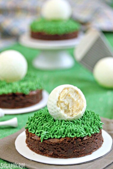 Close up of a Golf Ball Truffle and Putting Green Brownie with a bite removed from the truffle to show the interior and more brownies in the background.