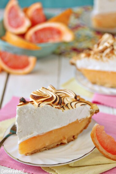 Grapefruit Meringue Pie slice with grapefruit slices in the background.