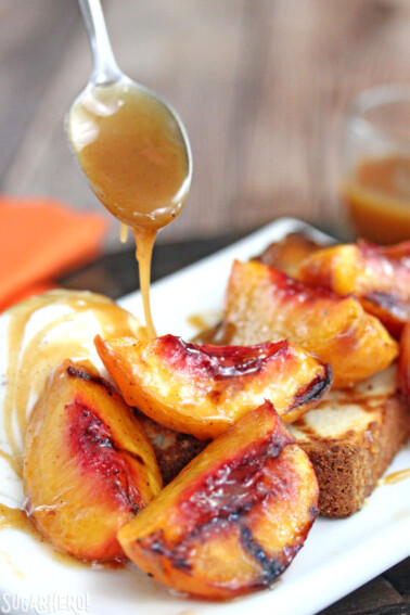 Spoon drizzling honey butter sauce over peaches.