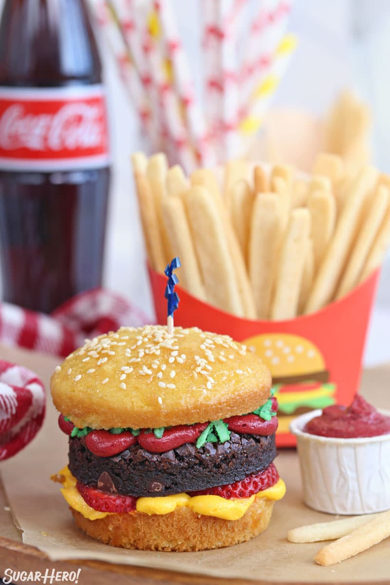 A hamburger cupcake with sugar cookie french fries and a bottle of Coke