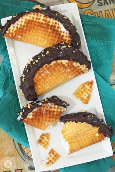 Three homemade choco tacos on a platter with the third broken into pieces.