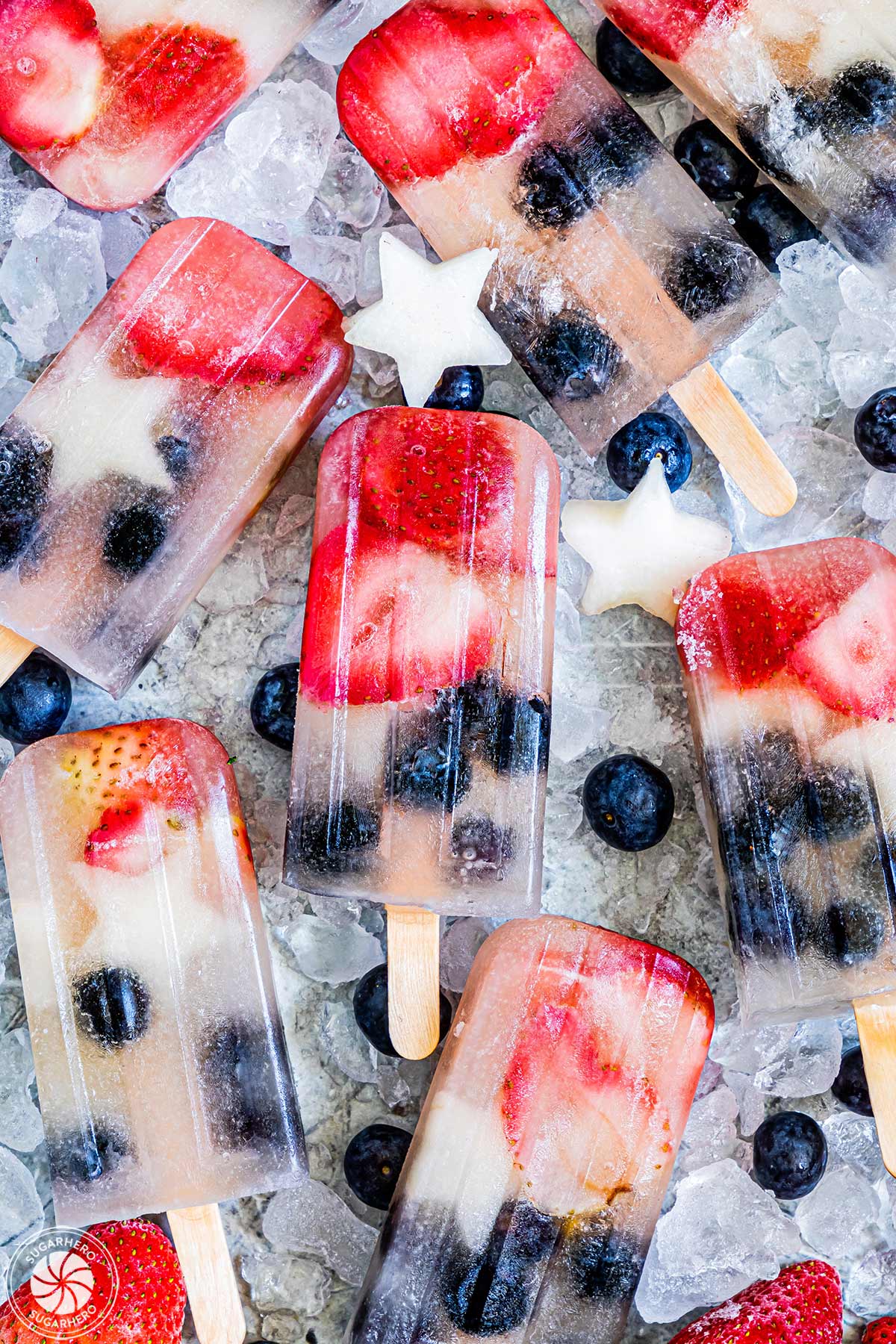 Homemade Fruit Popsicles on a bed of ice with fruit scattered around