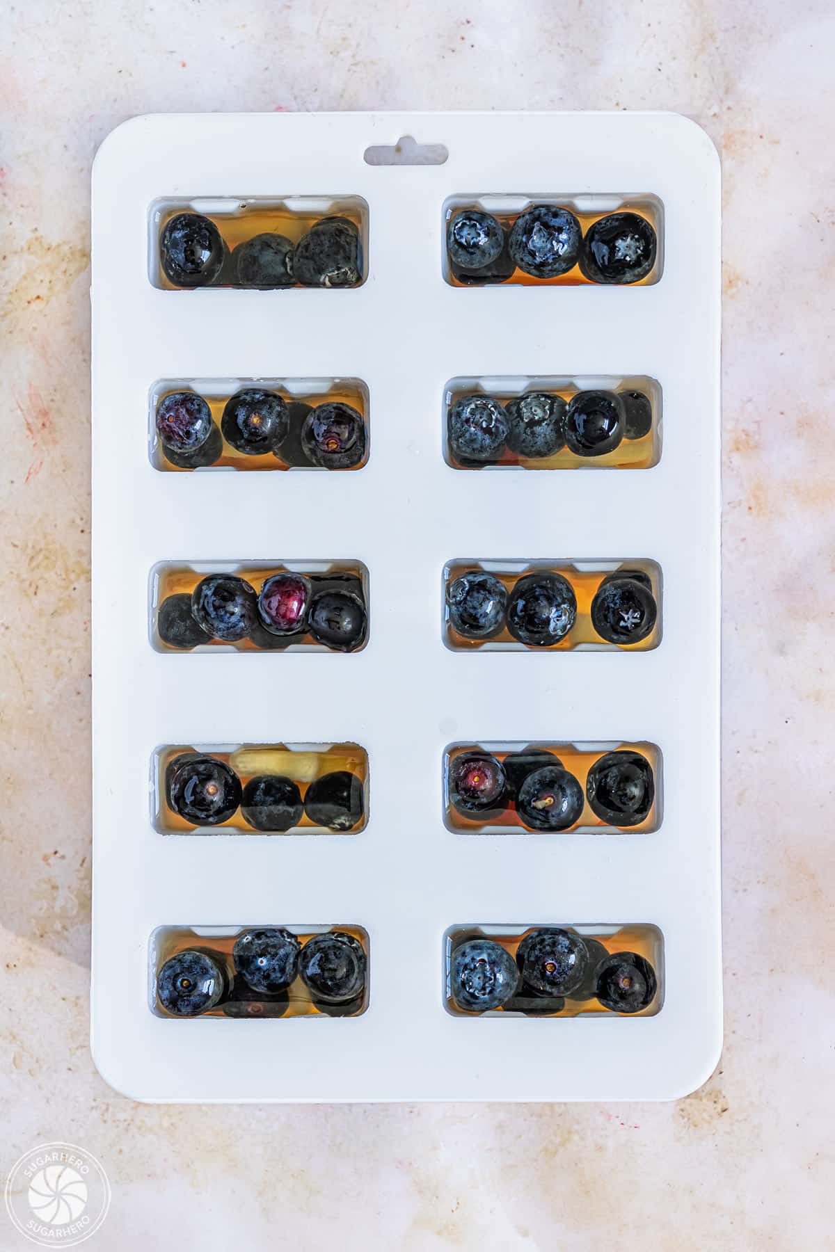 Top view of a popsicle mold filled with juice and fruit.