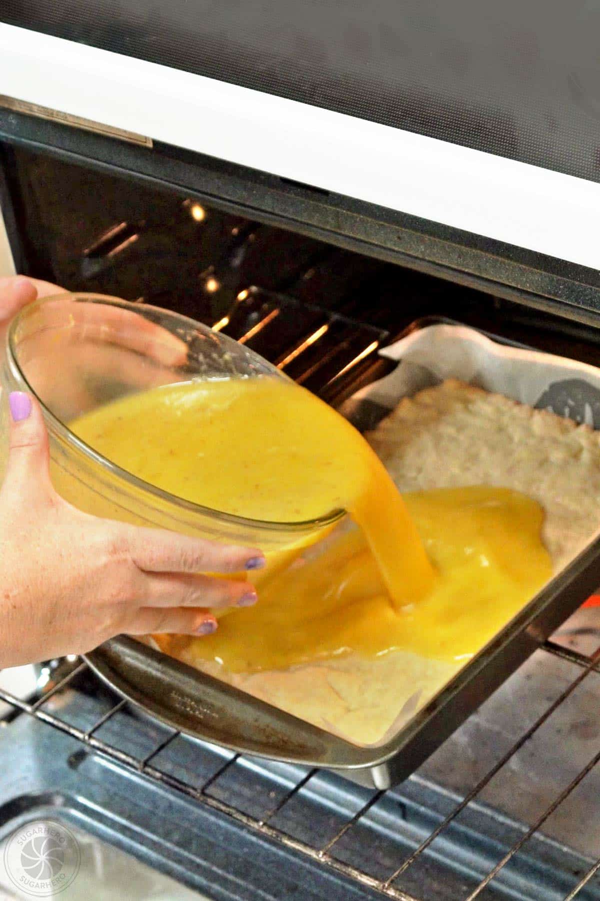 Hand pouring the Lavender Lemon Bar filling into the baking pan over partially baked crust.