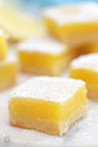Close up of a lemon bar with more bars in the background.