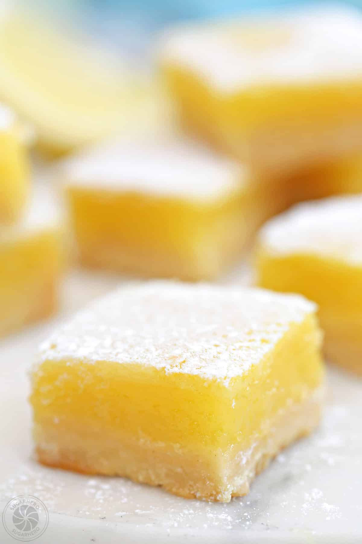 Close up of a lemon bar with more bars in the background.