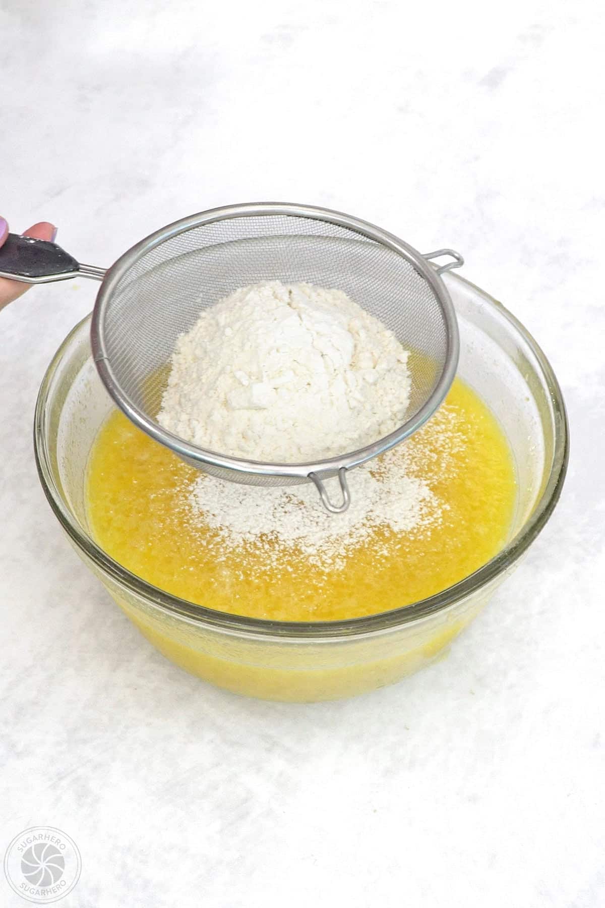 Flour being sifted into the filling for lemon bars.