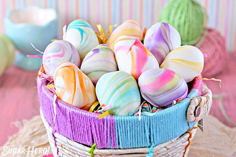 Marbled Easter Egg Truffles in a woven Easter basket with a pastel striped background.