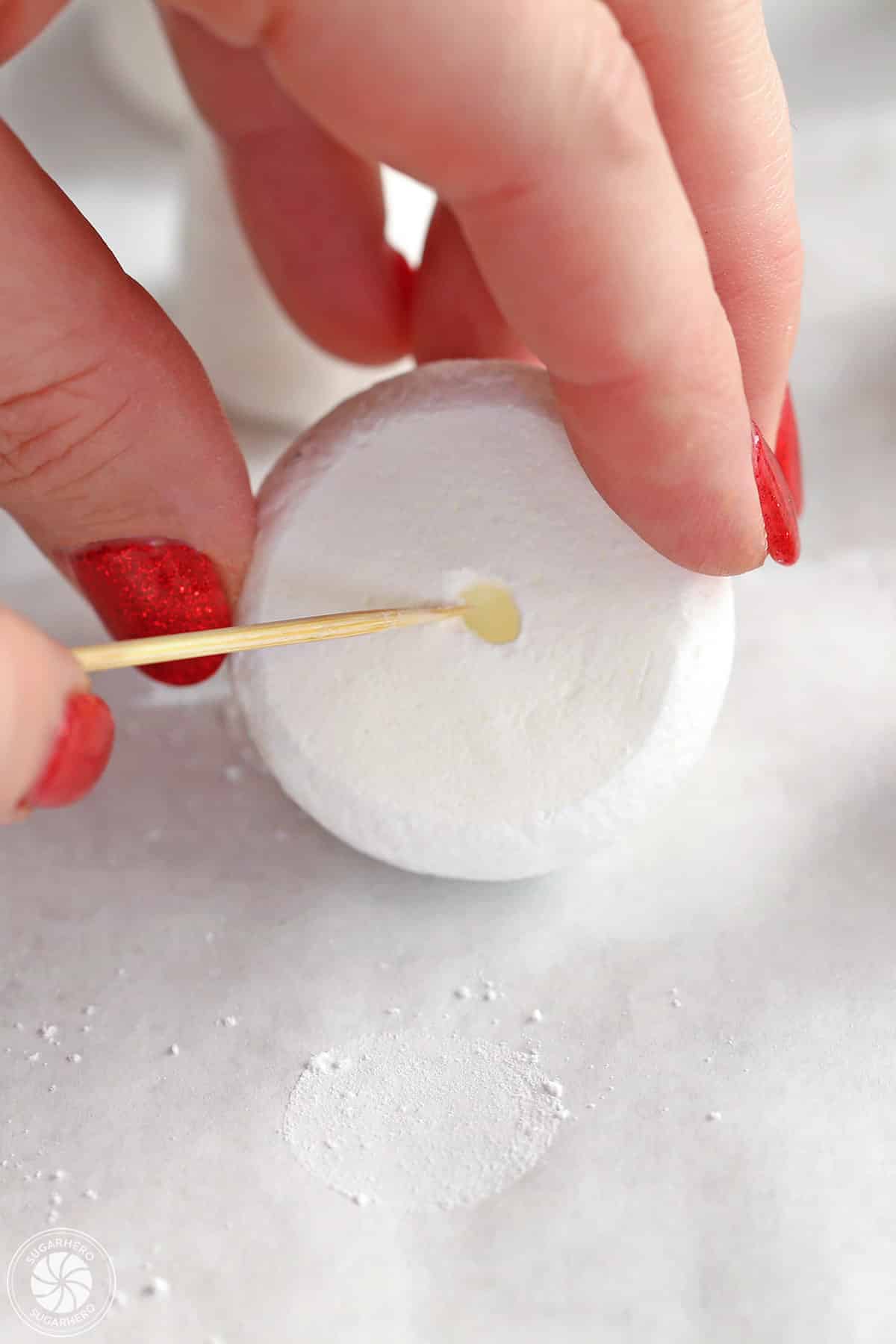 Hollowing out the base of a meringue mushroom cap with a toothpick.
