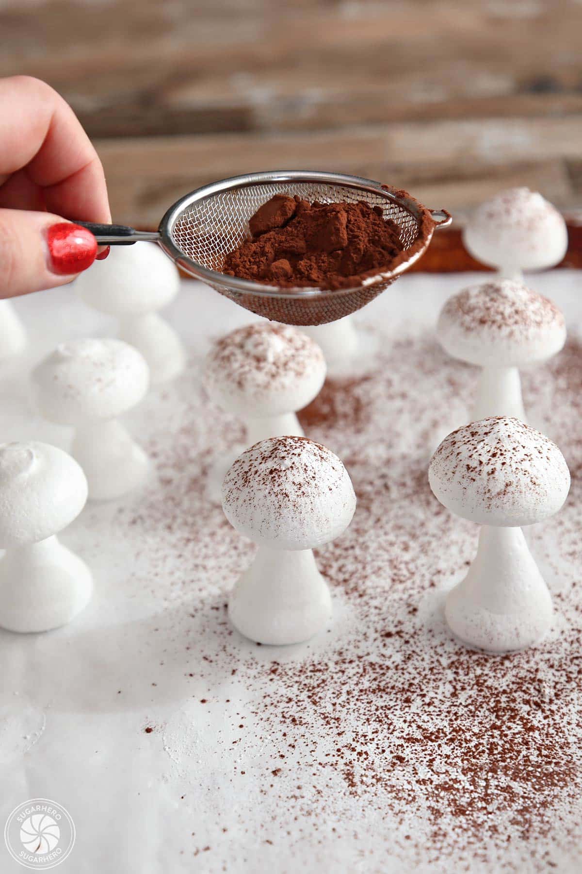 Sifting cocoa powder on top of meringue mushrooms.