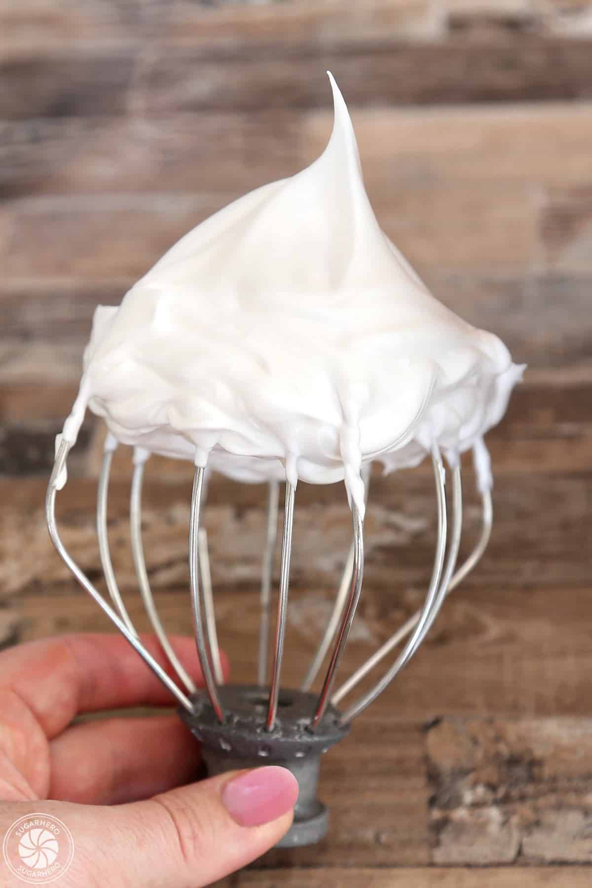 A whisk displaying egg whites whipped to firm peaks.