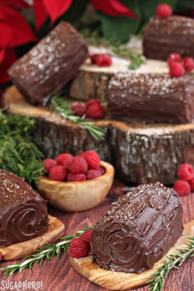 Mini Buche de Noel on a wooden surfaces with rosemary and raspberries.