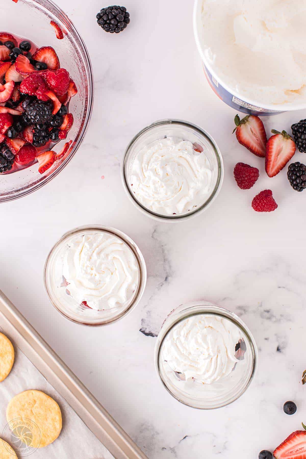 Swirls of whipped creasm on top of mixed berries in mason jars.