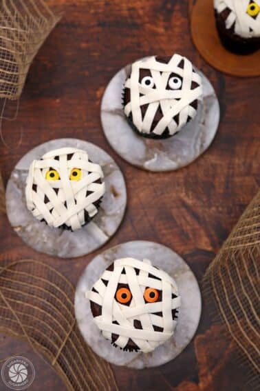 Top view of three Mummy Cupcakes on small marble discs.