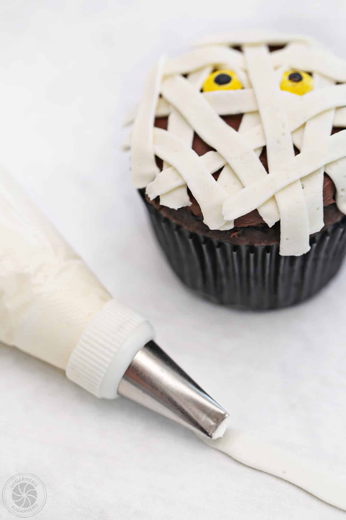 A Mummy Cupcake next to a bag of frosting with a basket weave tip.