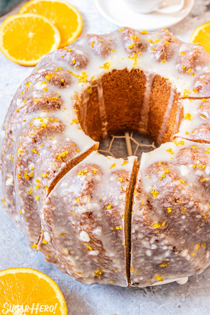 Orange bundt cake on a wire rack, sliced into pieces.