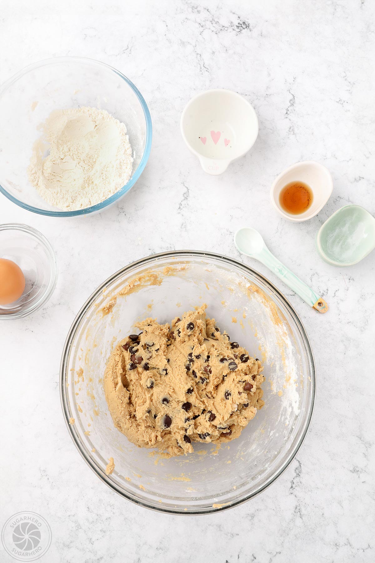 Mixing chocolate chip cookie dough in a large glass bowl.