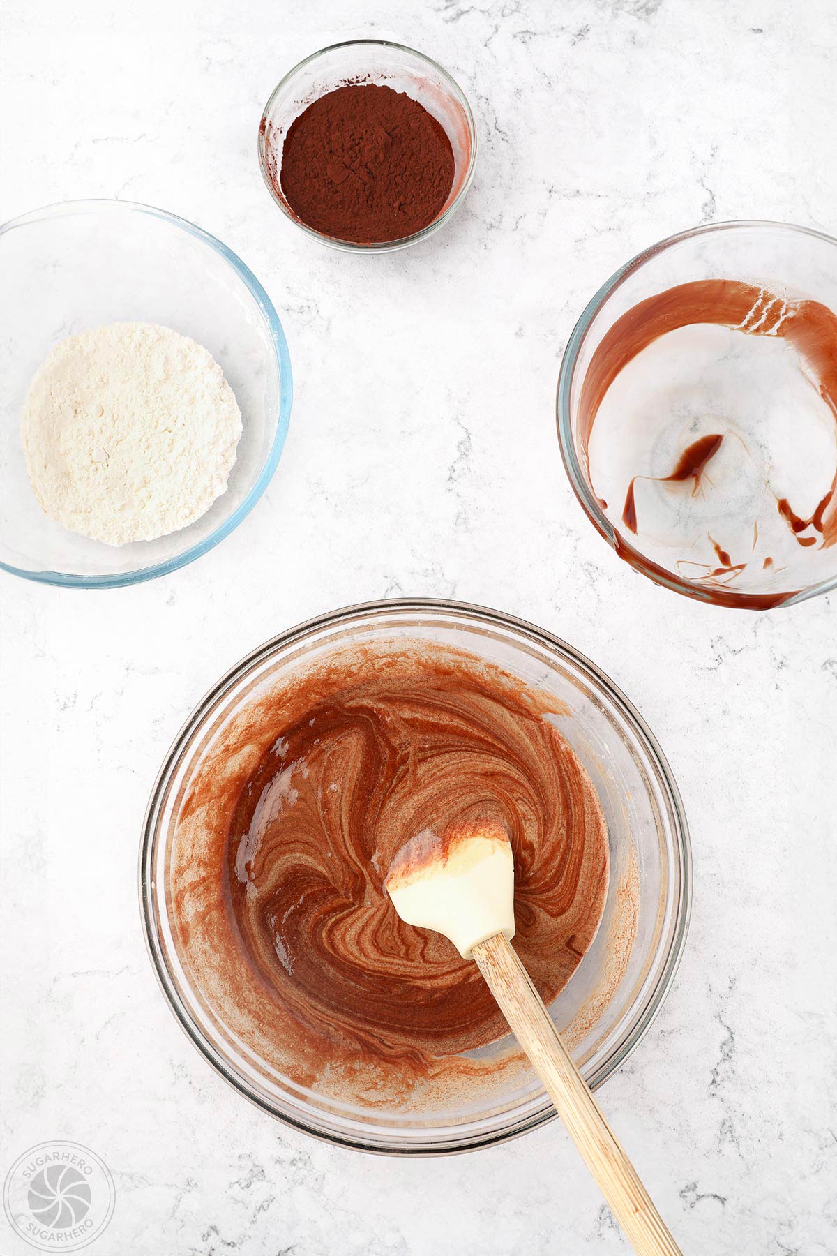 Combining eggs and melted chocolate in a glass bowl to make brownie batter.