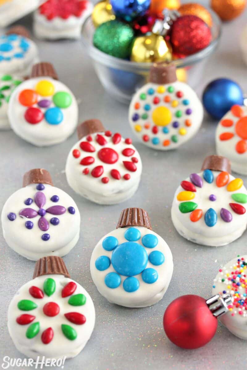 Oreo Cookie Christmas Ornaments on a glittery background with colorful ornaments scattered around.