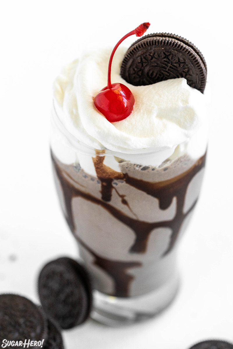 Oreo Milkshake in a glass with whipped cream, a cherry on top, and an Oreo.