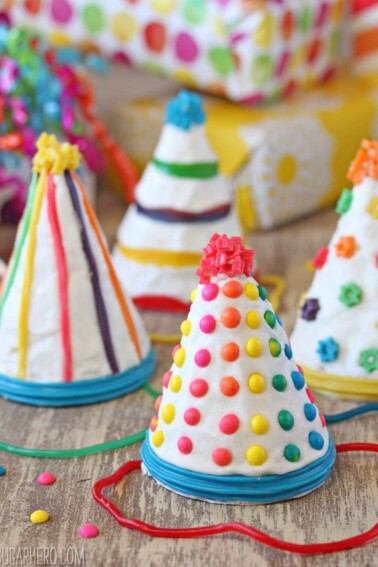 Four Birthday Party Hat Cakes on a wooden surface.