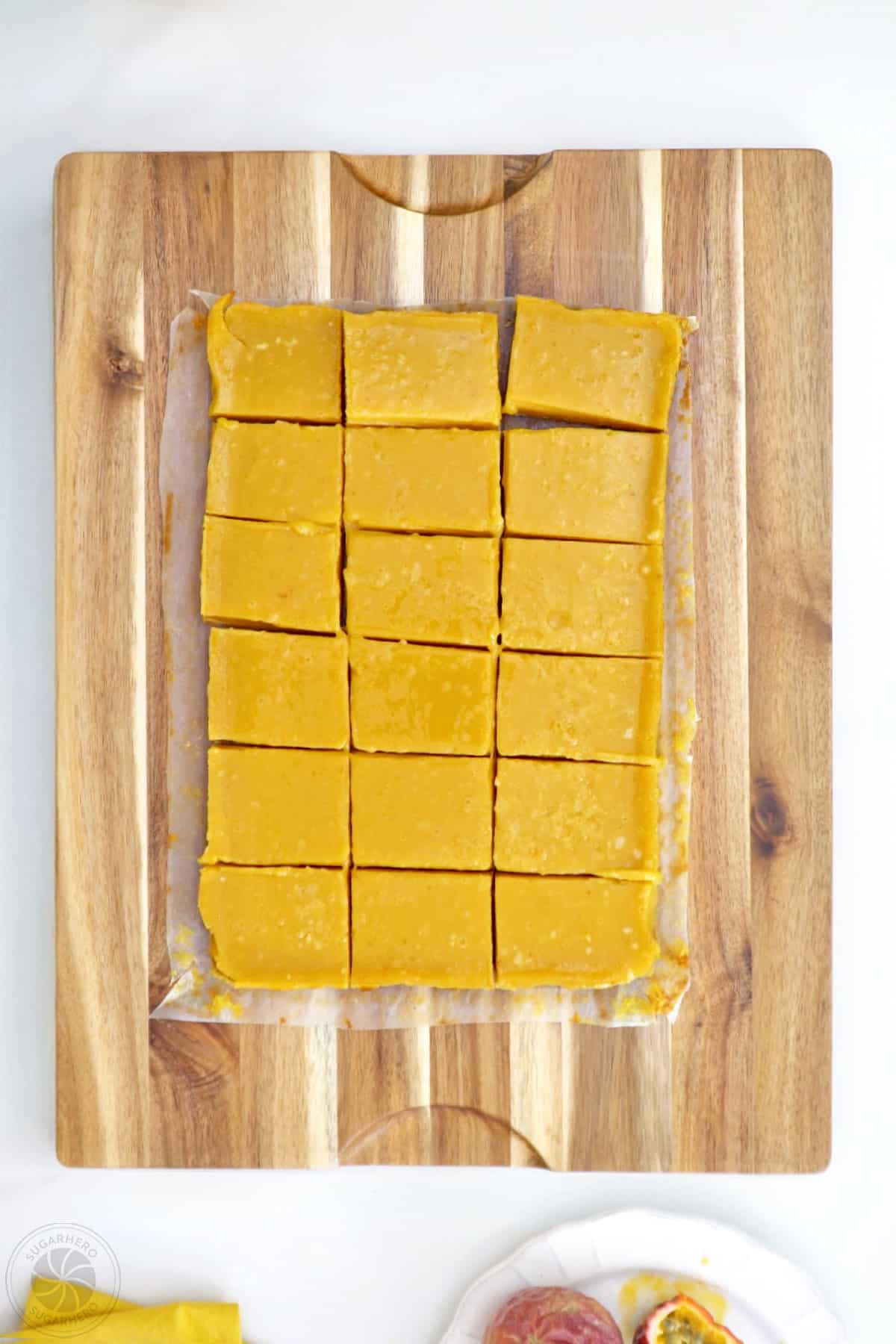 Overhead shot of passion fruit bars cut up on a wooden cutting board.