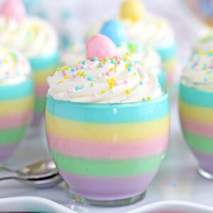 Close up of a pastel rainbow gelatin cup with 6 other cups in the background.