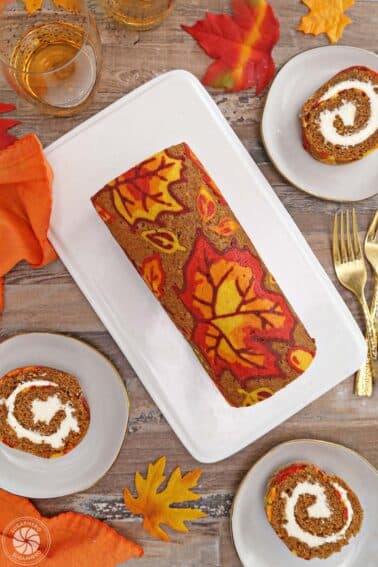 Overhead shot of patterned pumpkin roll with slices displayed around.