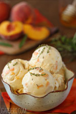 A bowl of peach of honey ice cream with peaches in the background.