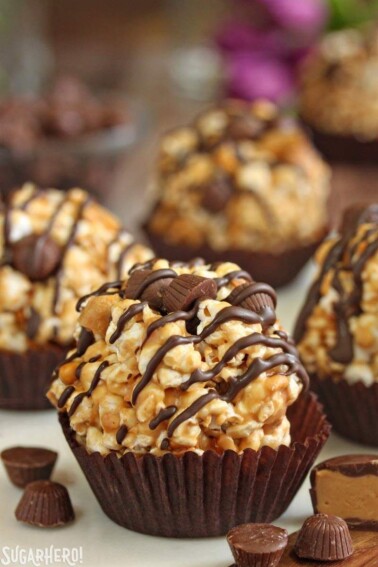 Close up of a peanut butter cup popcorn ball surrounded by mini peanut butter cups.