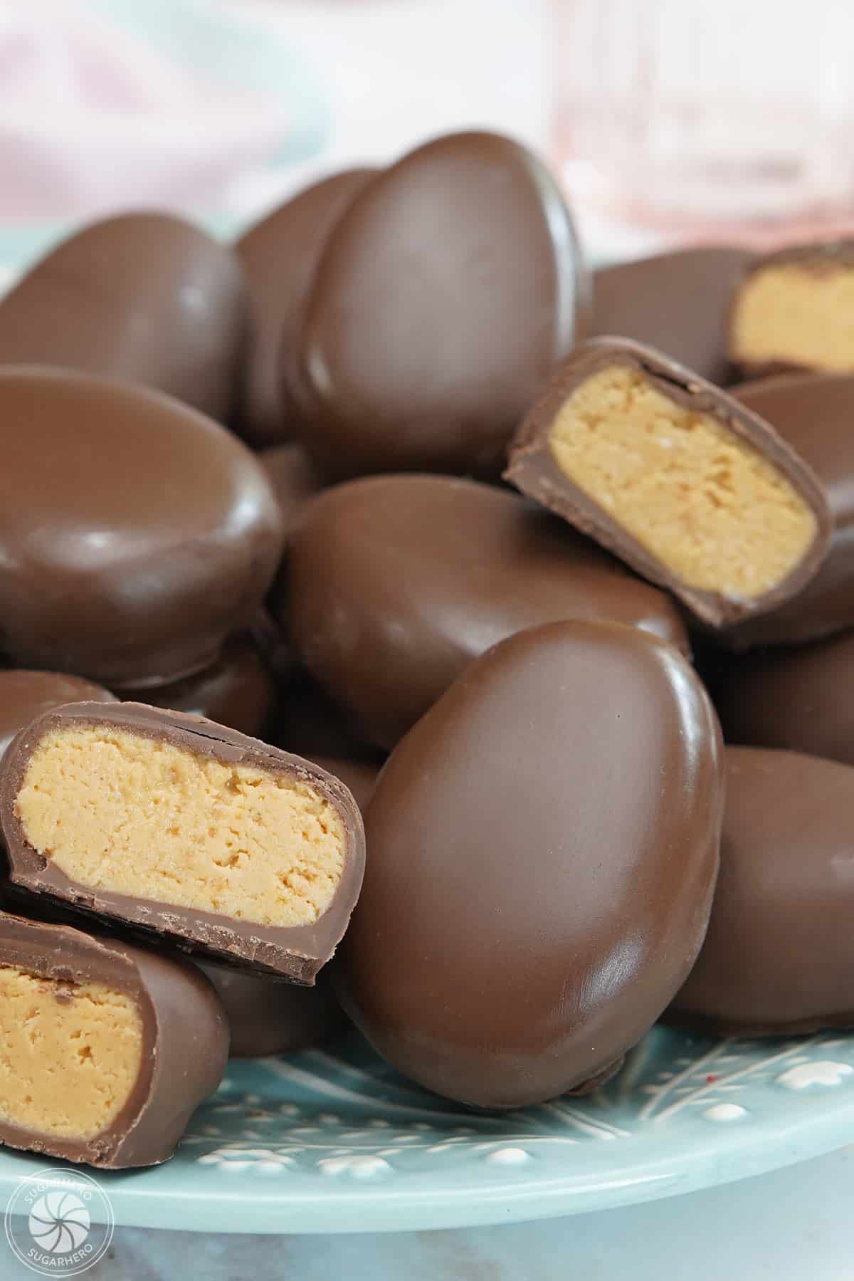 A teal plate holding peanut butter eggs with some eggs cut in half to show the filling.