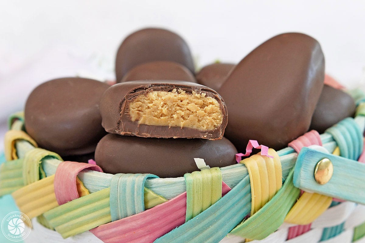 Peanut butter eggs in a colorful Easter basket with one egg cut in half to show the center.