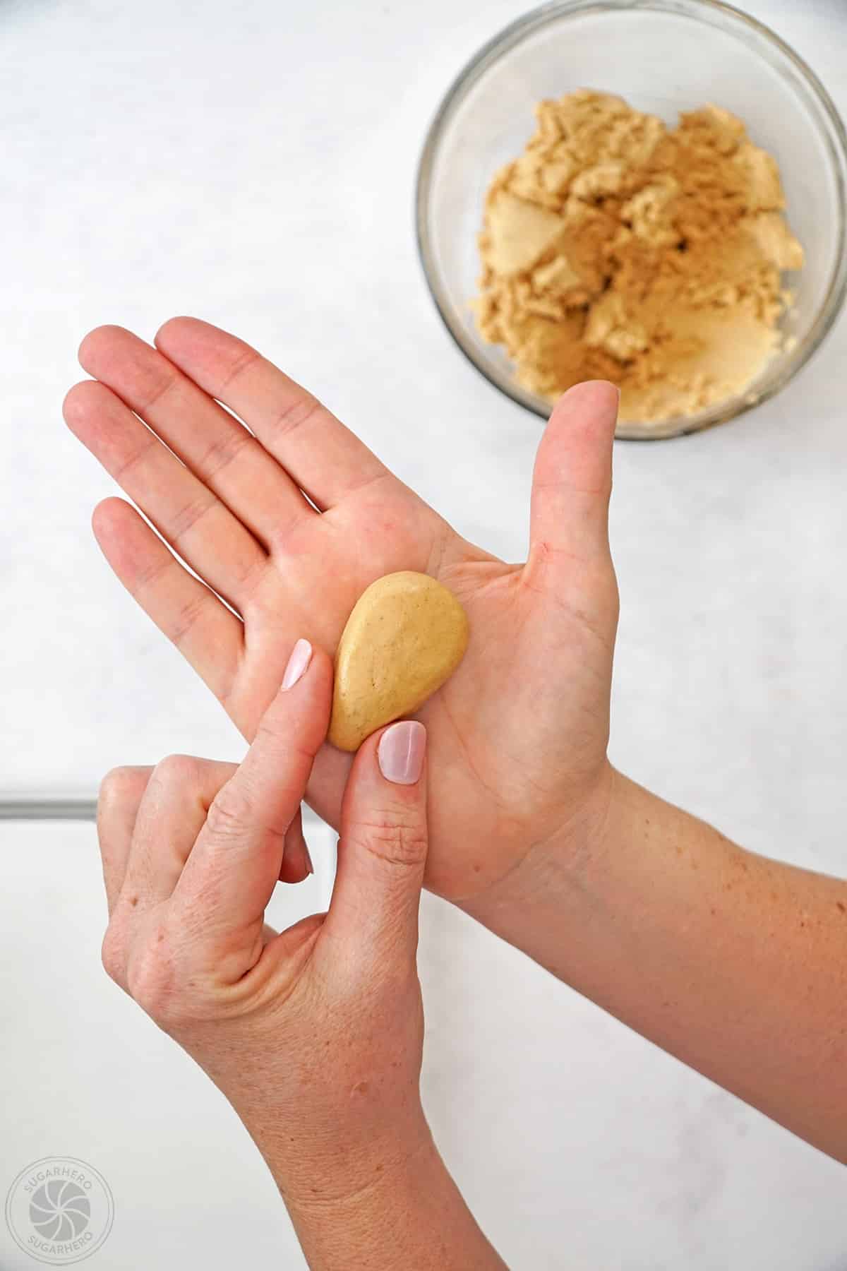 A hand shaping peanut butter filling into the shape of an egg.