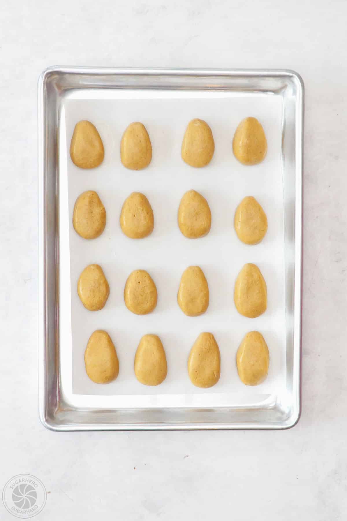 Shaped peanut butter filling on a lined baking sheet.
