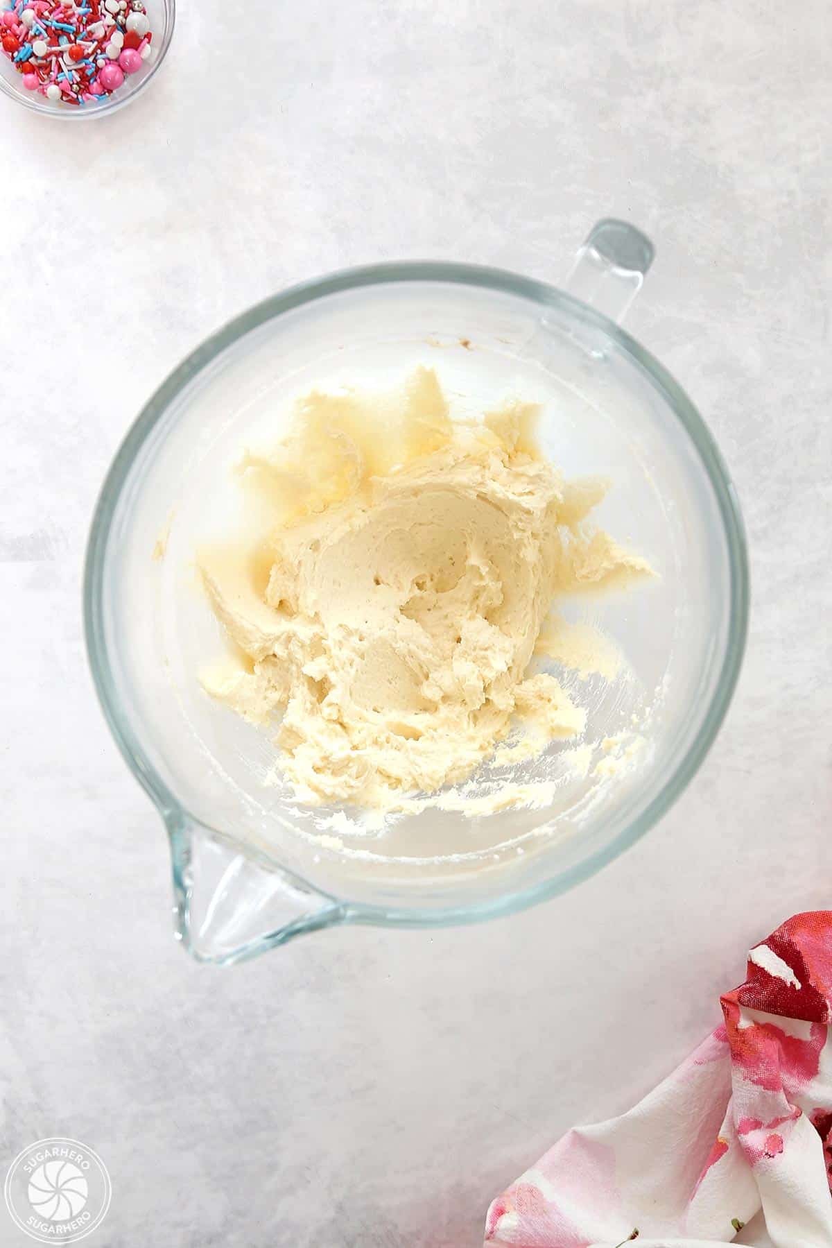Clear glass mixing bowl with creamed ingredients inside.