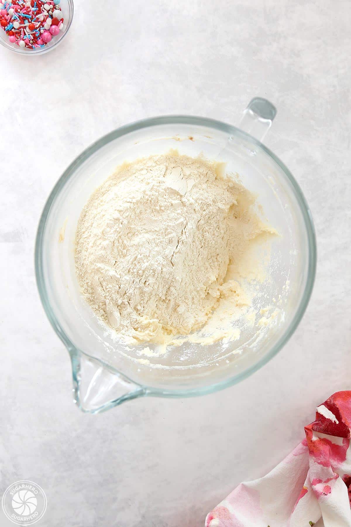 Clear glass mixing bowl with flour inside.