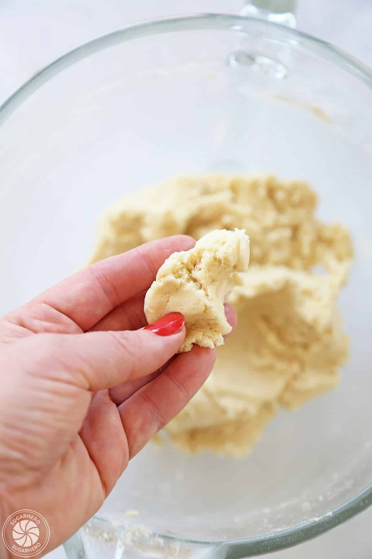 Hand holding a pinch of sugar cookie dough to show the soft but not sticky texture.