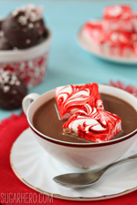 2 Peppermint Swirl Marshmallows in a cup of hot chocolate with hot chocolate truffles in the background.