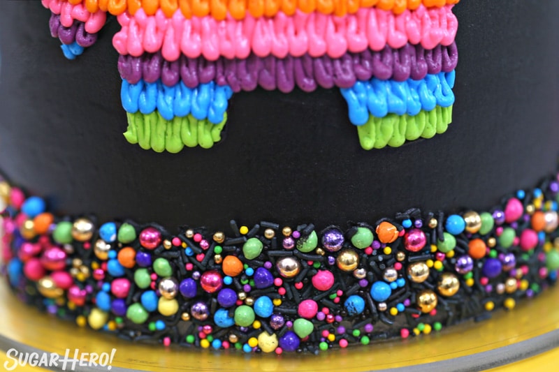 Close-up of colorful sprinkle border on black pinata cake