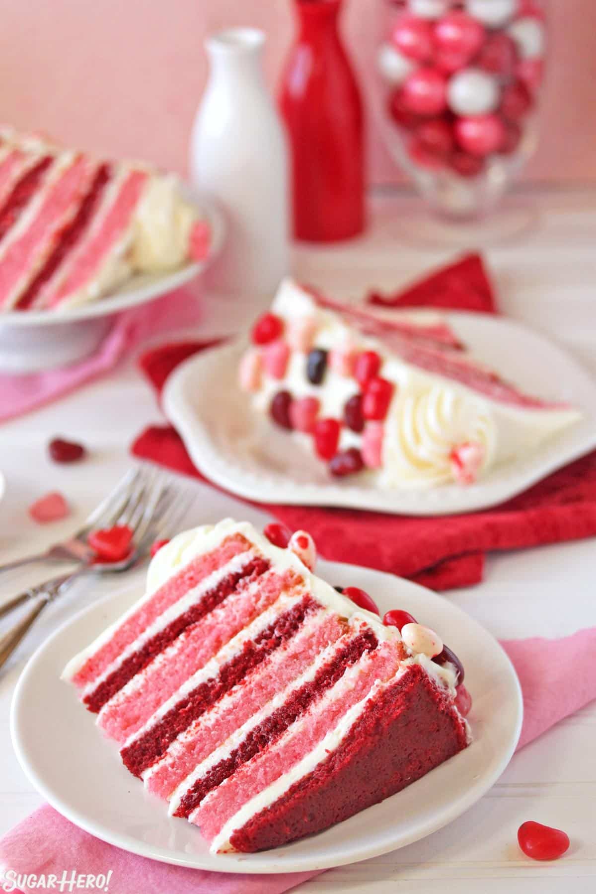 Three slices of pink and red velvet cake on white plates.