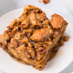 Slice of Pumpkin Bread Pudding on a white plate, drizzled with cinnamon syrup.