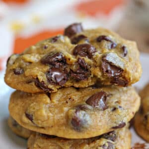 2 Pumpkin Chocolate Chip Cookies stacked one on top of the other with a bite removed from top cookie to show the gooey interior.