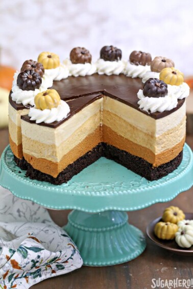 Pumpkin Chocolate Mousse Cake on a teal cake plate with a portion removed to show layers and a slice cut away.