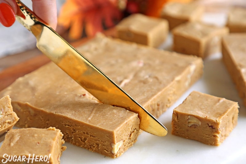 A shot of pumpkin fudge being cut with a gold knife
