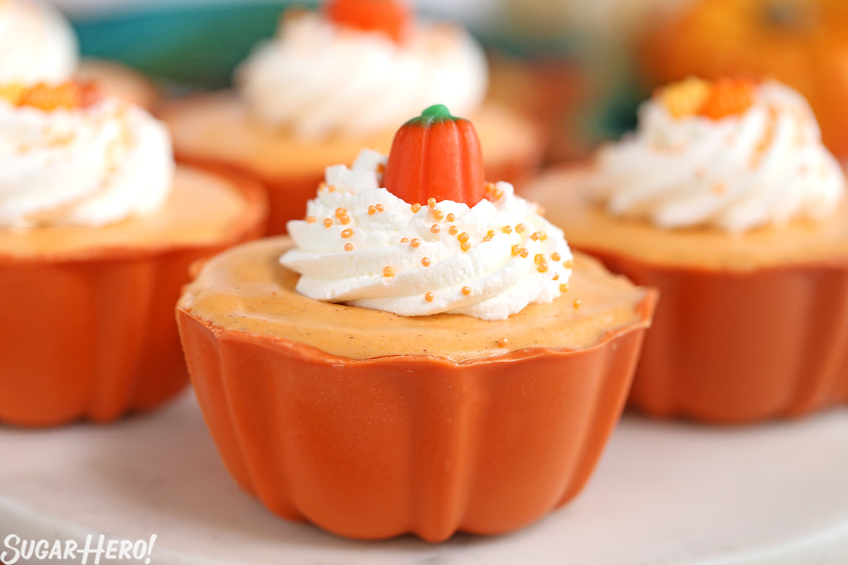 Pumpkin Spice Mousse Cups - close-up of pumpkin spice mousse cup with whipped cream and candy pumpkin on top | From SugarHero.com