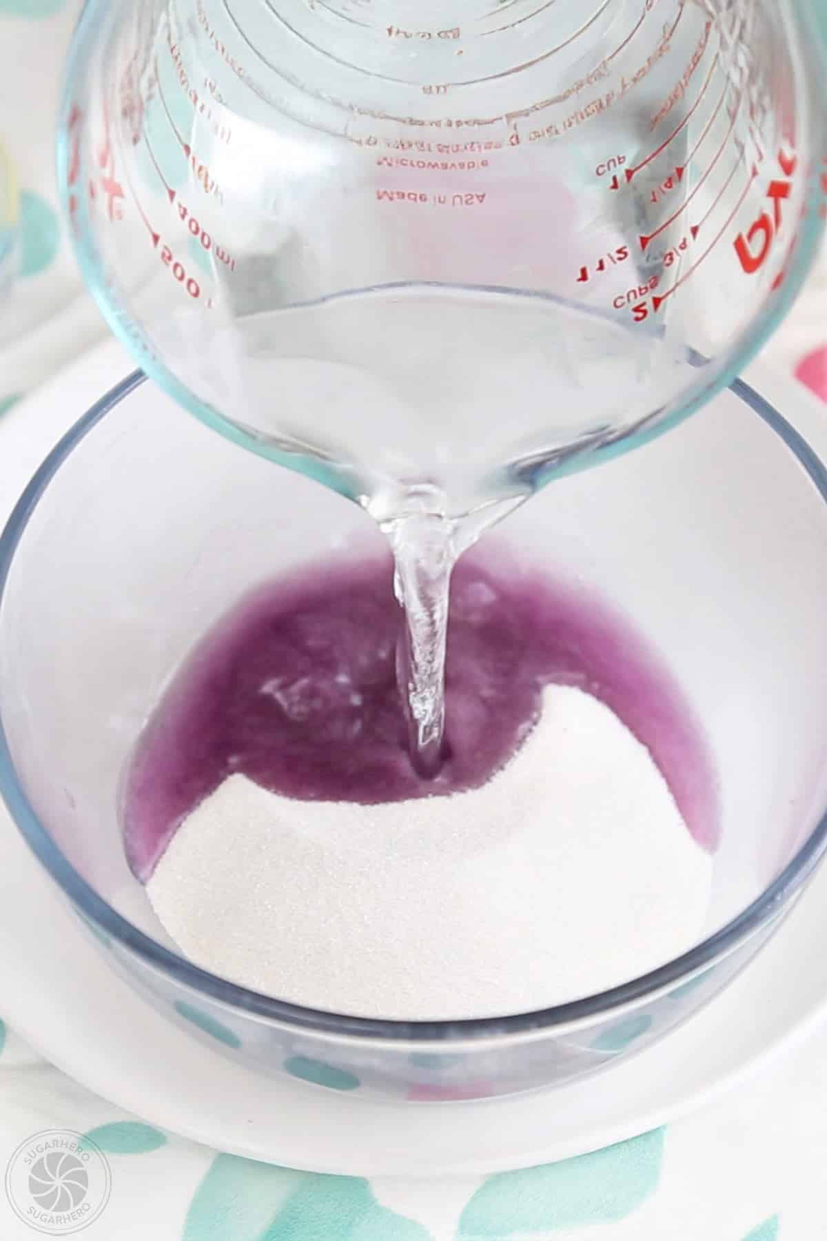 Hot water being poured into a mixing bowl with gelatin powder in it.