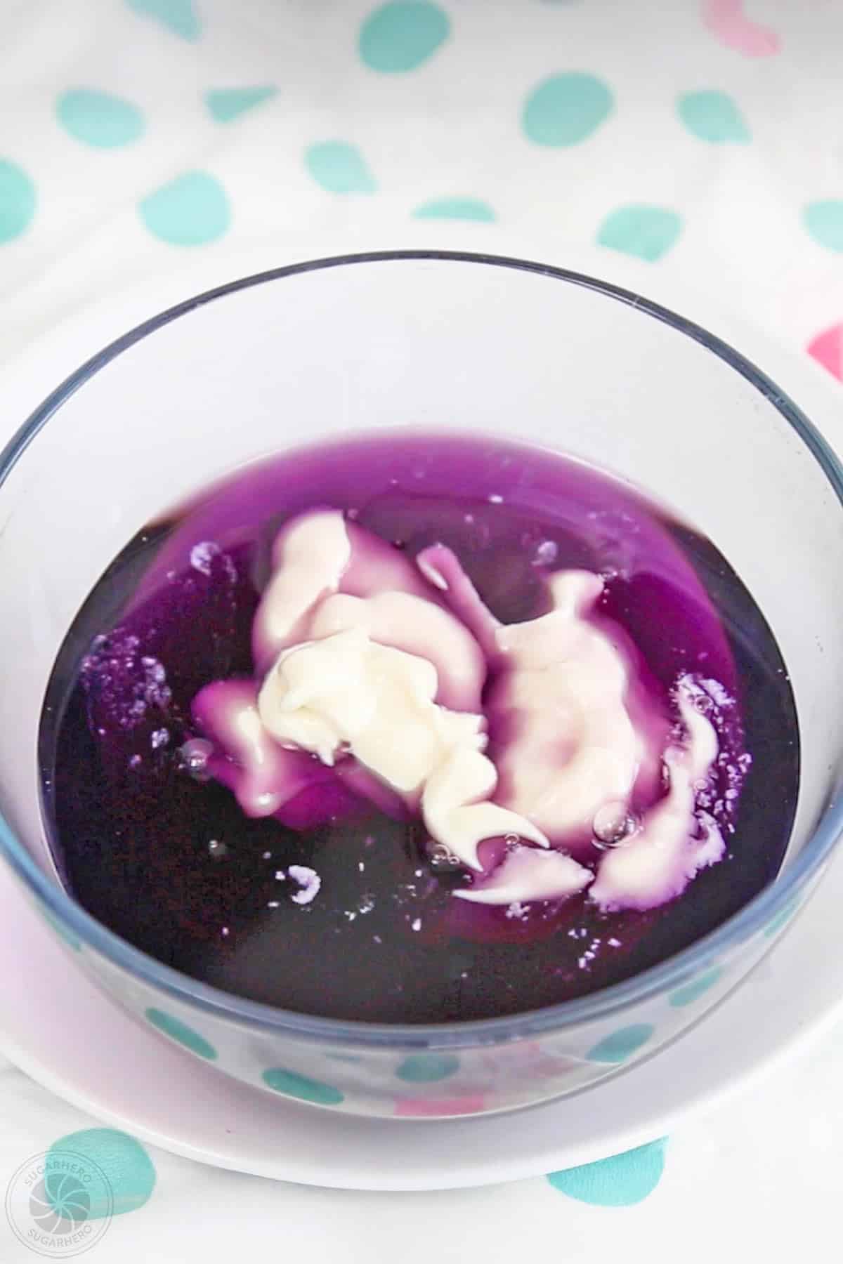 A bowl of purple gelatin with yogurt in it.