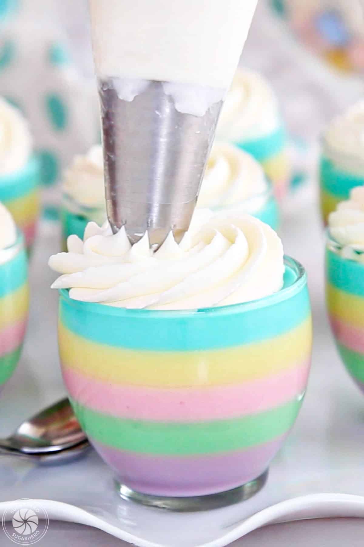 Piping whipped cream on top of a gelatin cup.
